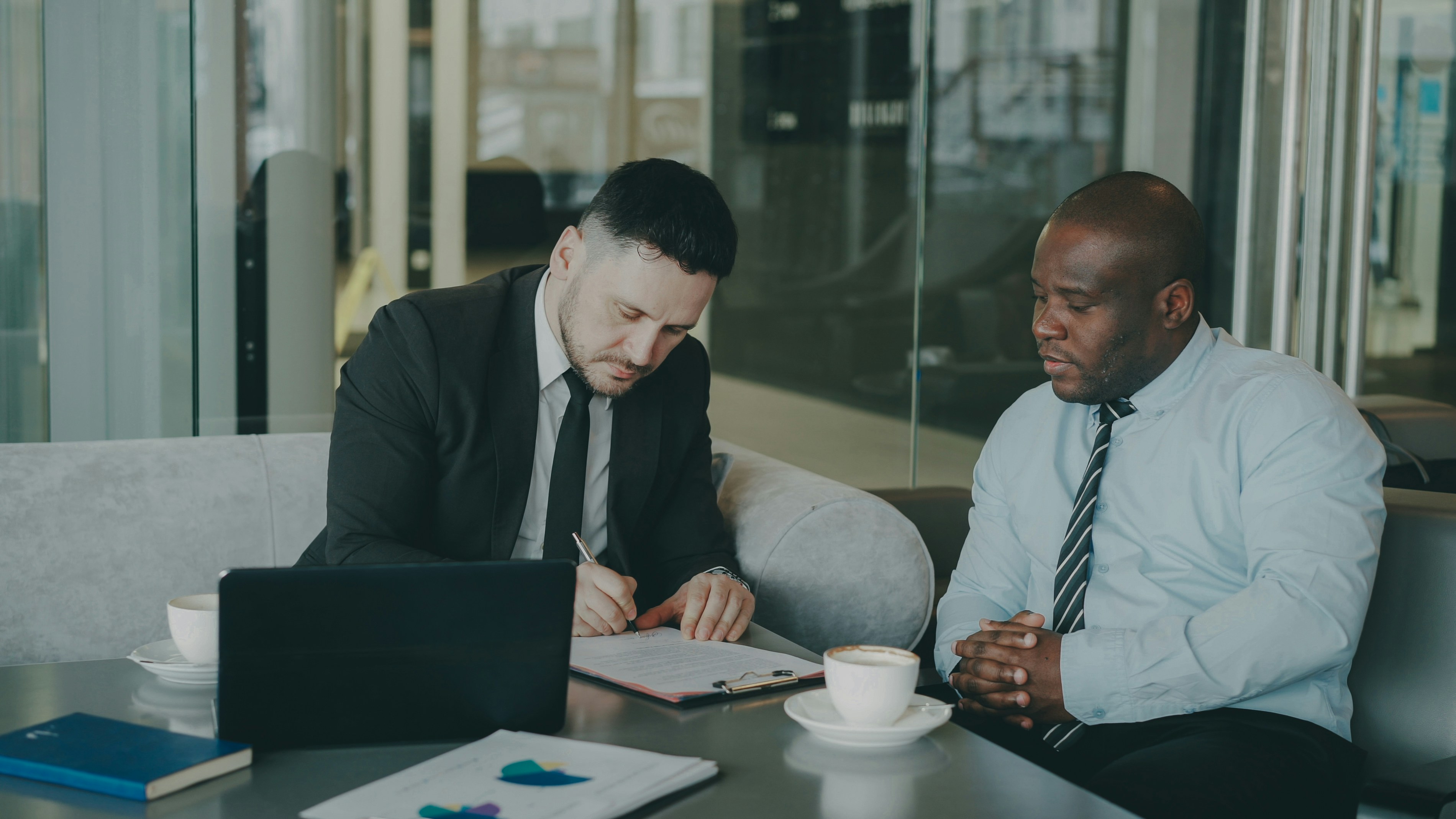 Two men having a meeting, one is signing a contract