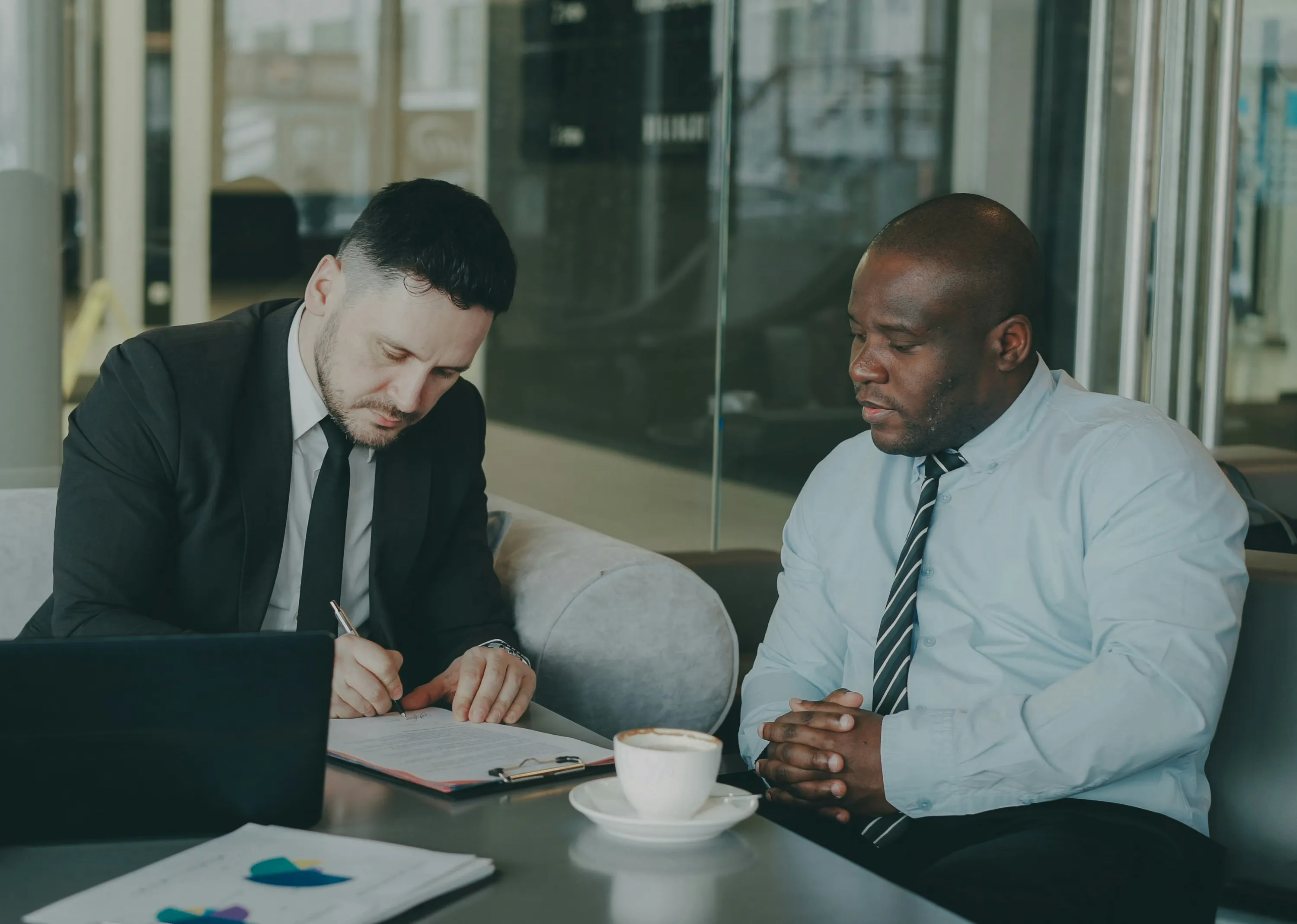 Two men having a meeting, one is signing a contract