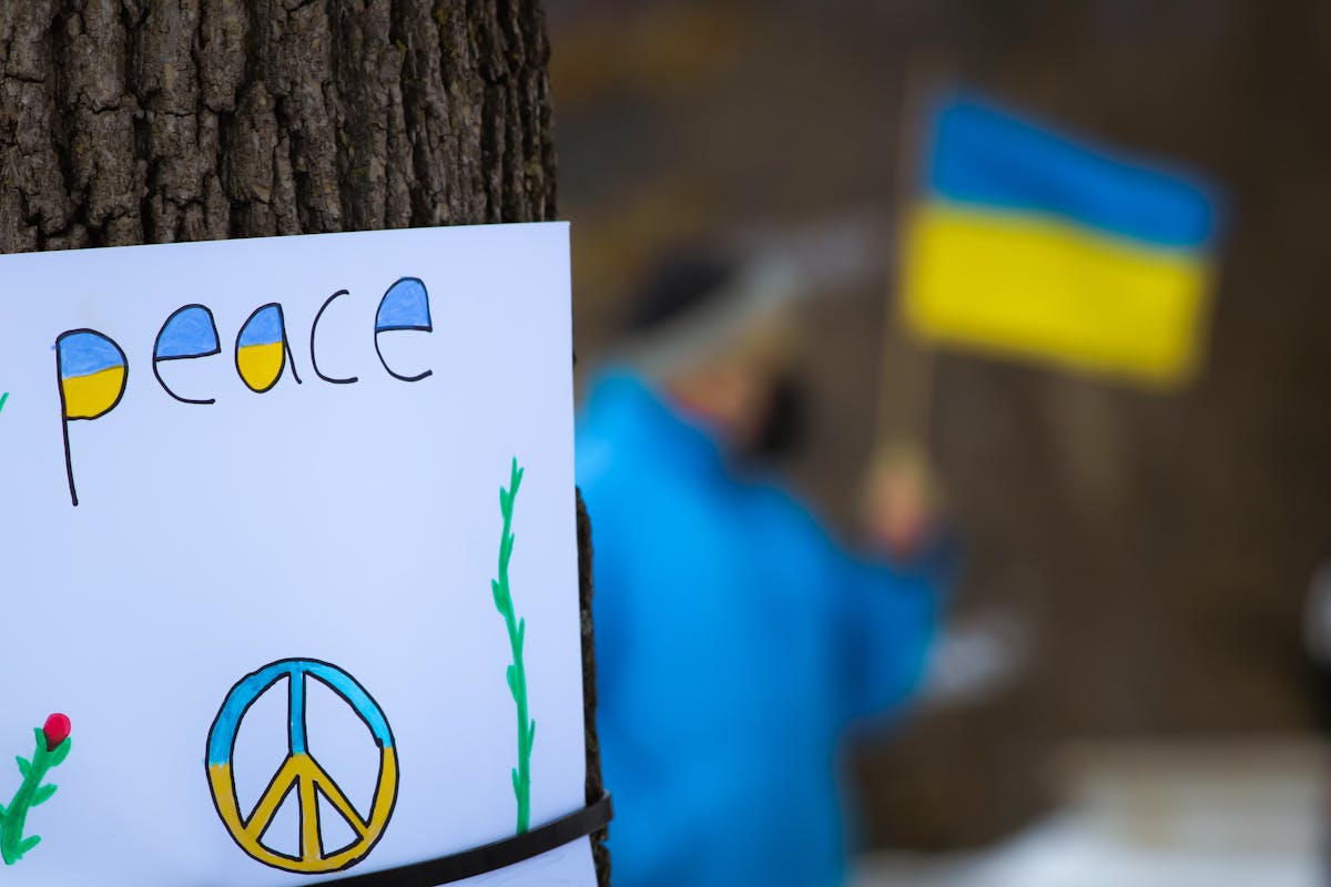 Peace in Ukraine sign on a tree with Ukraine flag out of focus