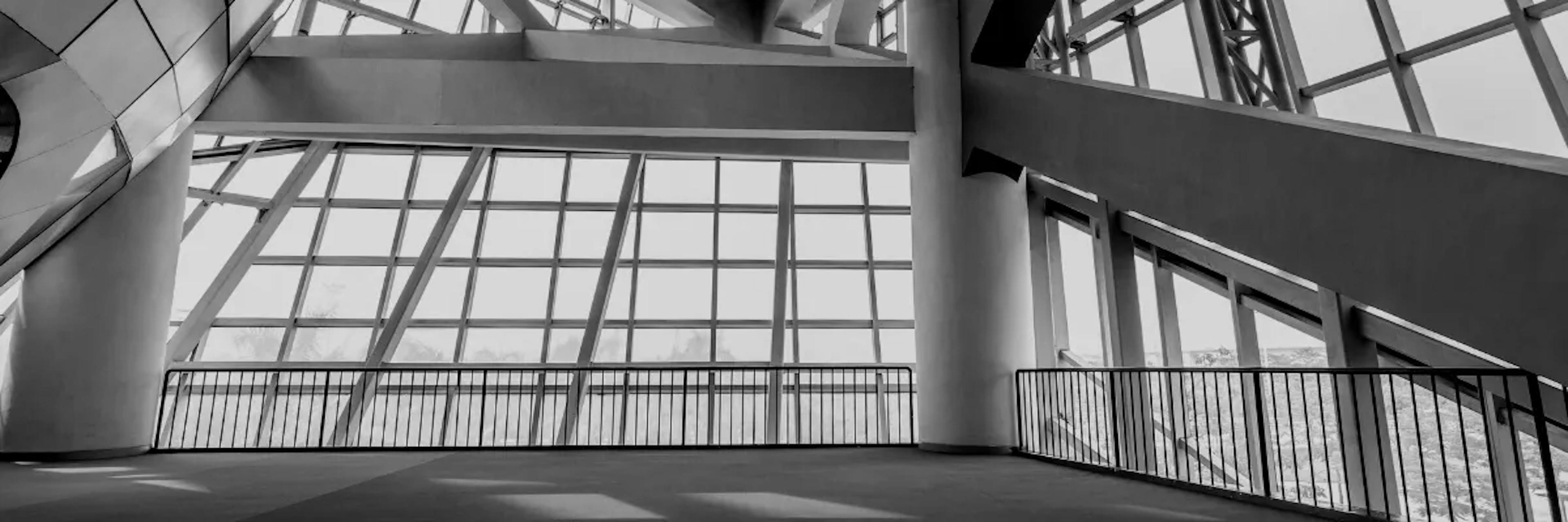 Black and white view of a building from interior facing a wall of windows