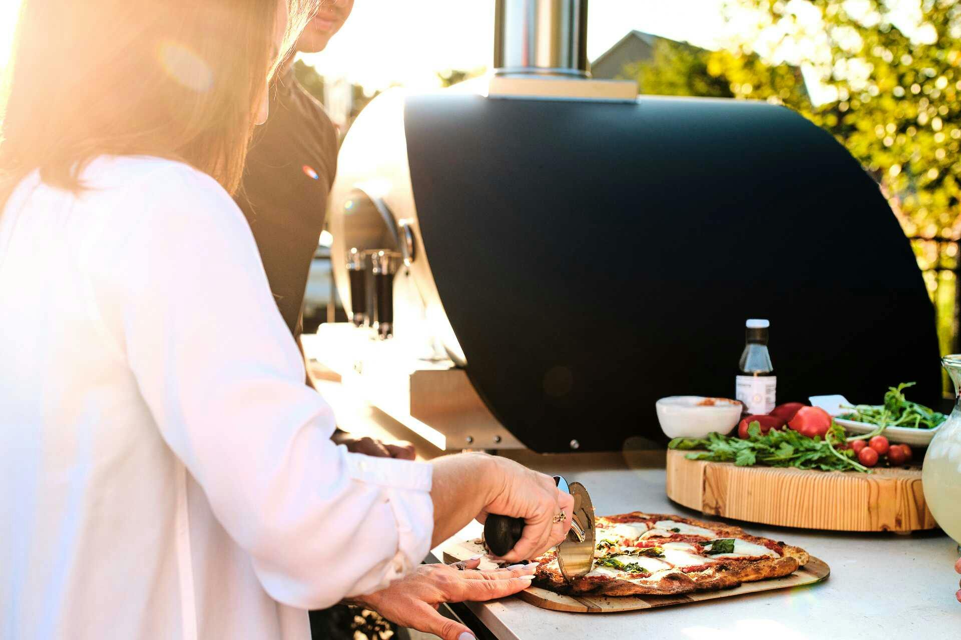 Woman making pizza in her Coyote wood fired pizza oven
