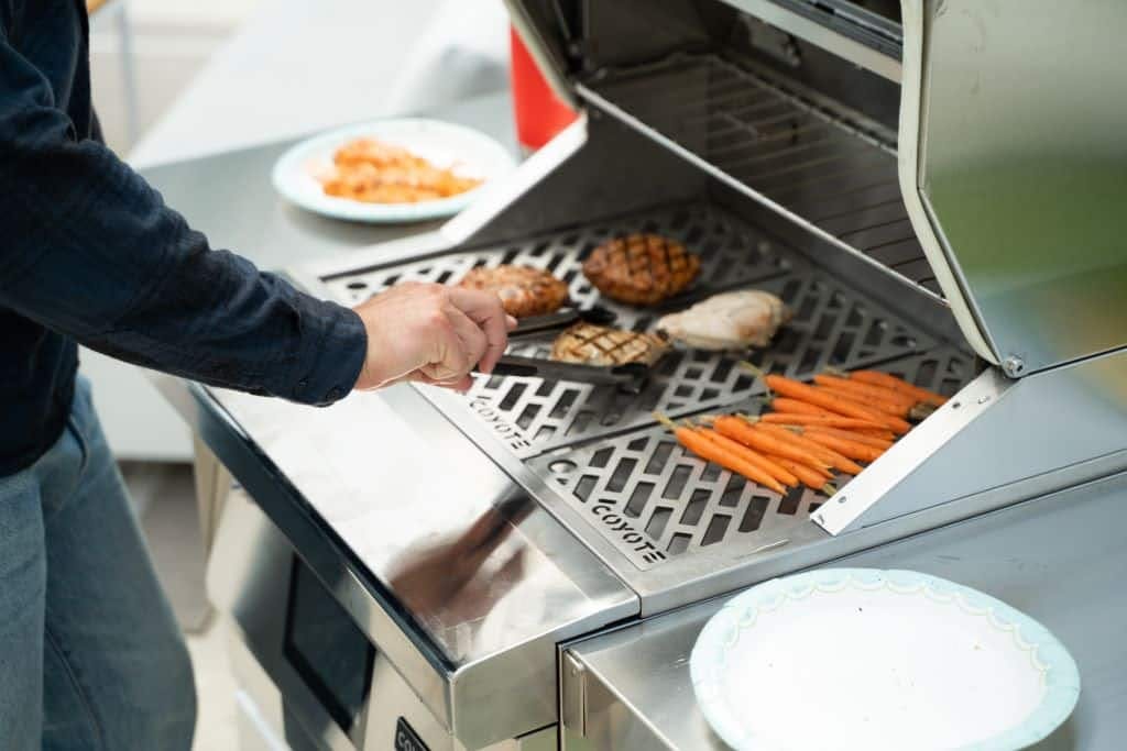 man cooking on coyote pellet grill