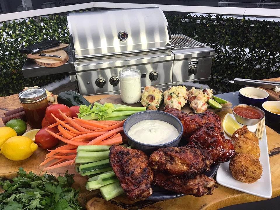 A large table's filled with sports themed appetizers with a grill in the background