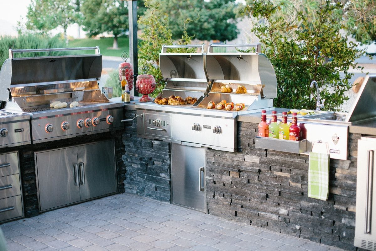 Meal being cooked on outdoor kitchen grills by Coyote