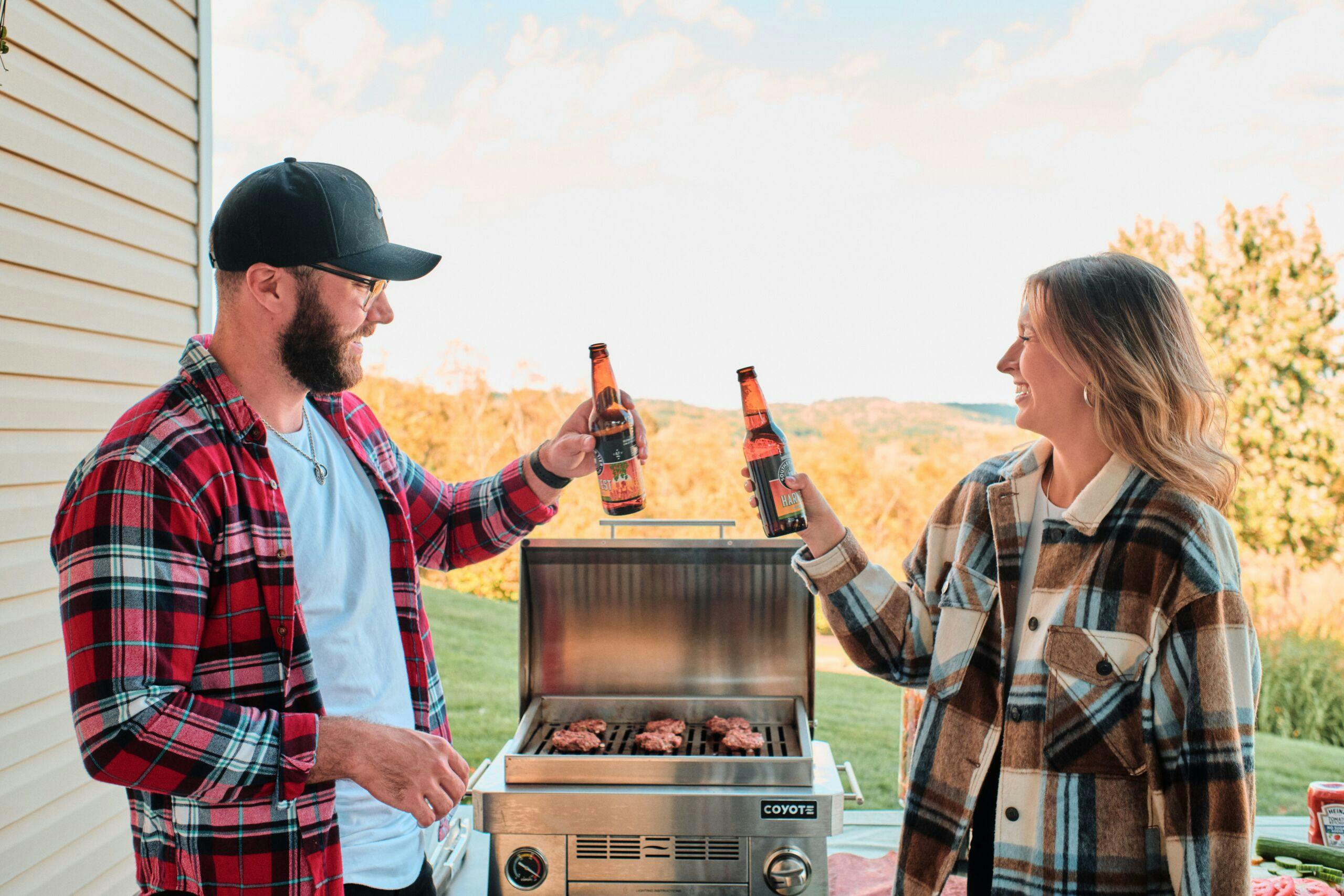 couple drinking beer by Coyote portable grill