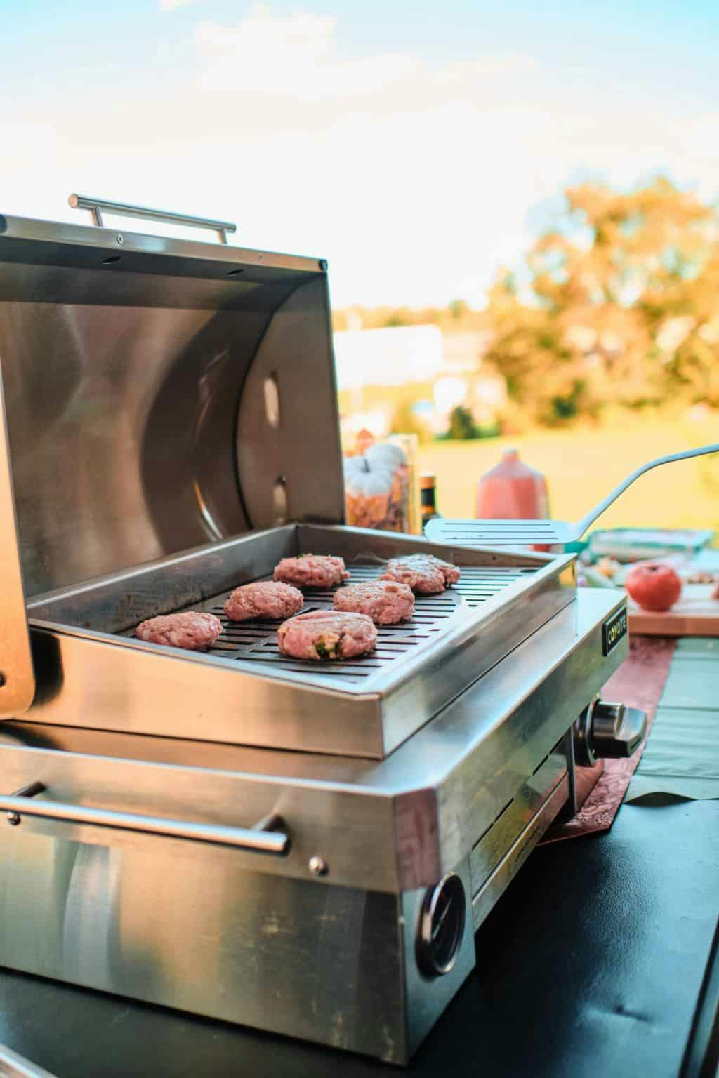 burgers being made on coyote portable grill