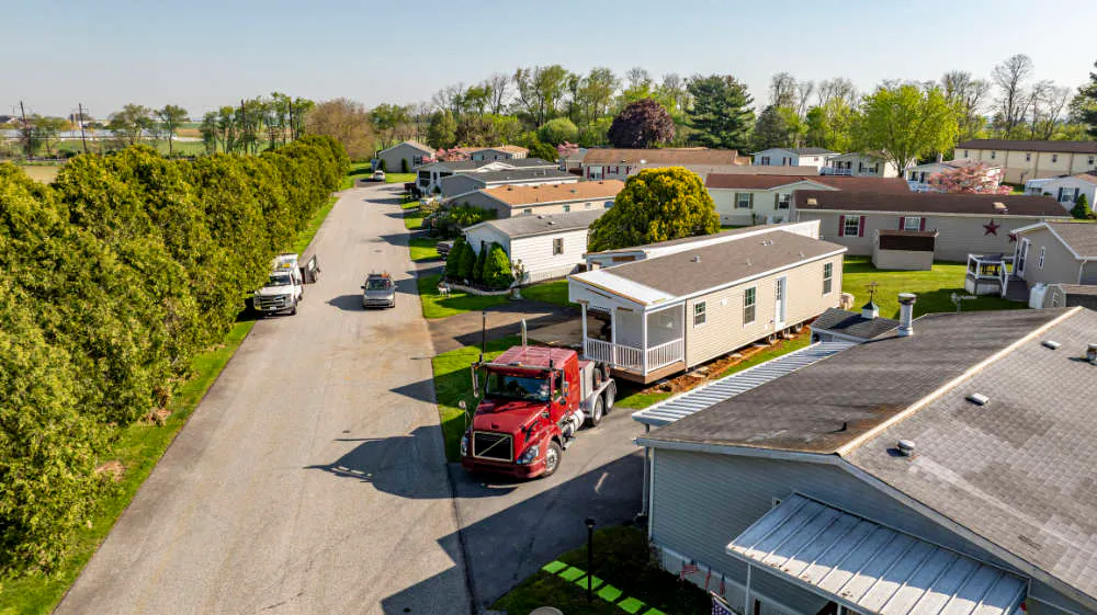 A truck delivers a manufactured modular home to a home site.