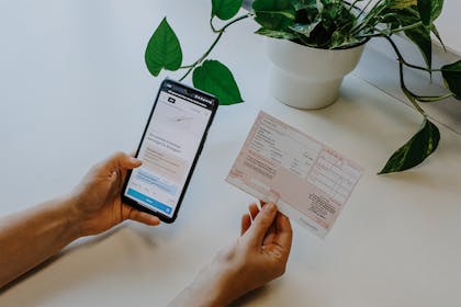 Frau hält Rezept und Handy in der Hand