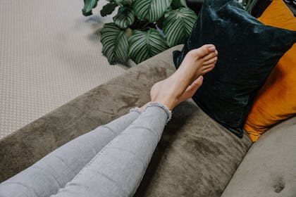 Frau liegt mit nackten Füßen auf dem Sofa