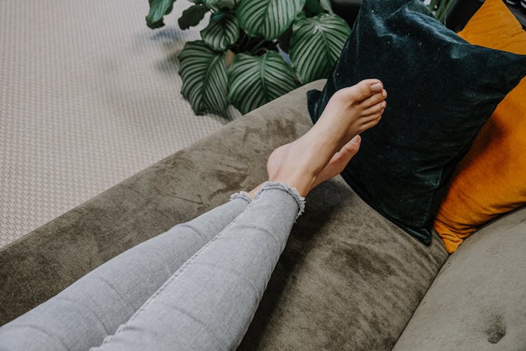 Frau liegt mit nackten Füßen auf dem Sofa