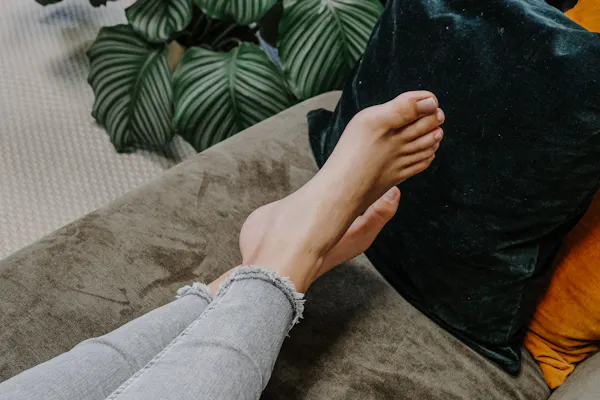 Frau liegt mit nackten Füßen auf dem Sofa