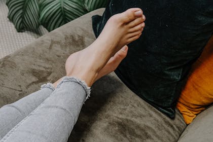 Frau liegt mit nackten Füßen auf dem Sofa