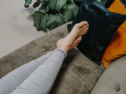 Frau liegt mit nackten Füßen auf dem Sofa