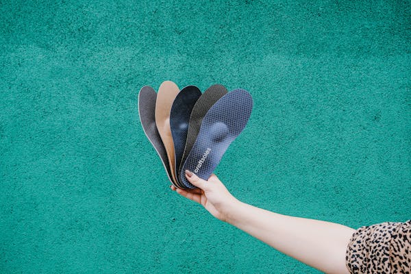 Frau hält Einlagenfächer vor einer grünen Wand