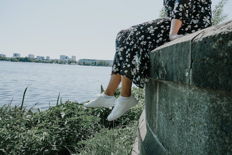 Frau sitzt auf Mauer