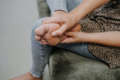 Frau hält schmerzenden Fuß in der Hand