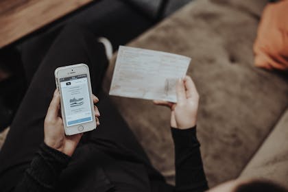 Frau hält Rezept und Handy in der Hand