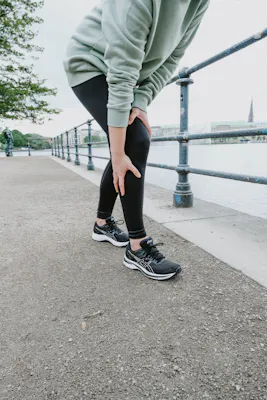  Frau greift beim Joggen an ihr schmerzendes Knie