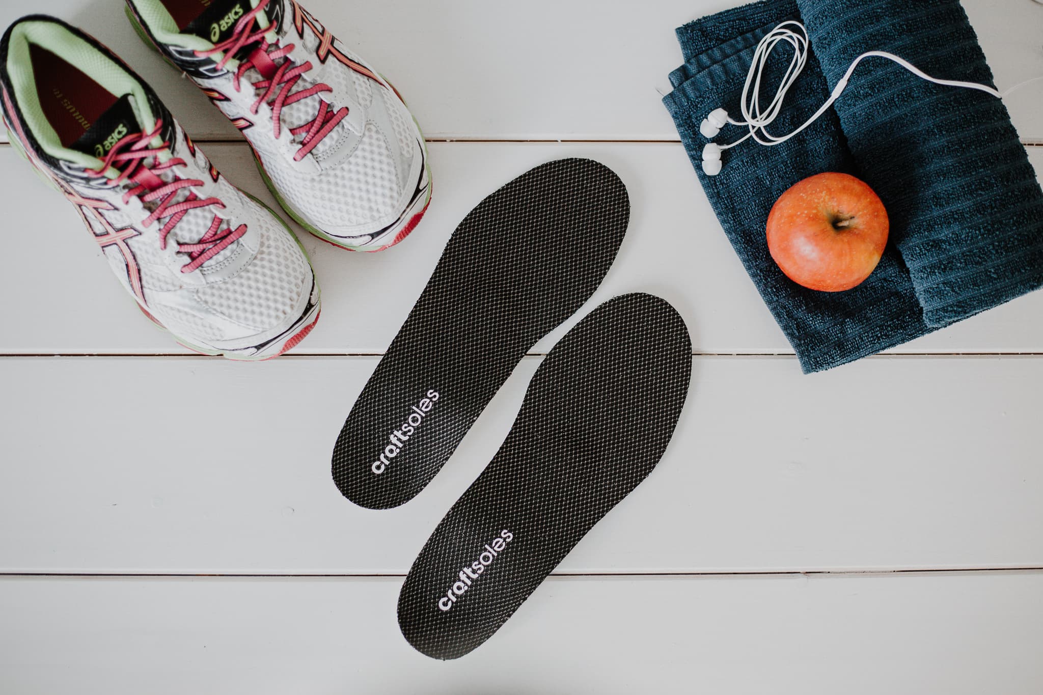 Schuhpaar, Einlage und Handtuch auf weißem Boden