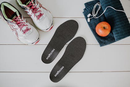 Schuhpaar, Einlage und Handtuch auf weißem Boden