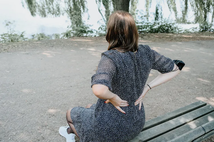 Frau hält sich den Rücken vor Schmerz