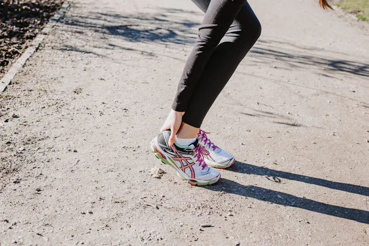 Frau greift sich an Achillessehne