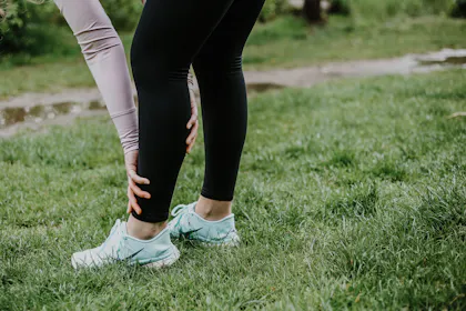 Frau greift sich an schmerzendes Schienbein