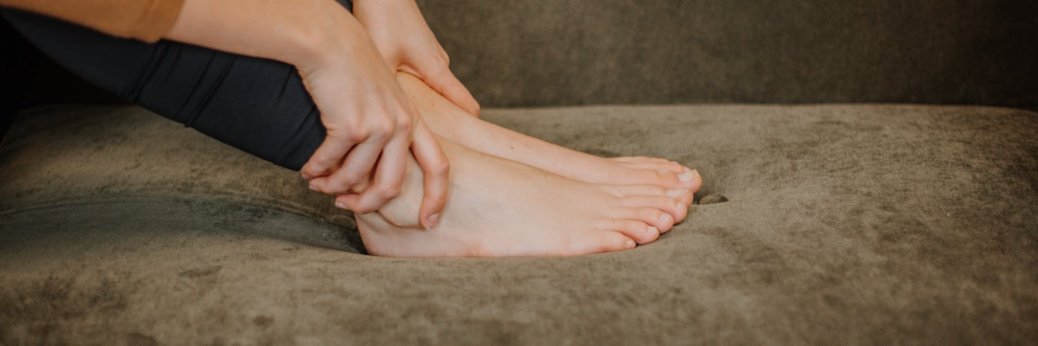 Frau greift sich an schmerzendes Sprunggelenk