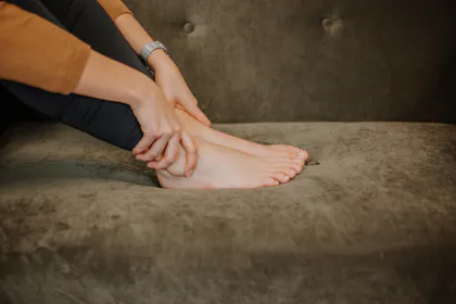 Frau greift sich an schmerzendes Sprunggelenk