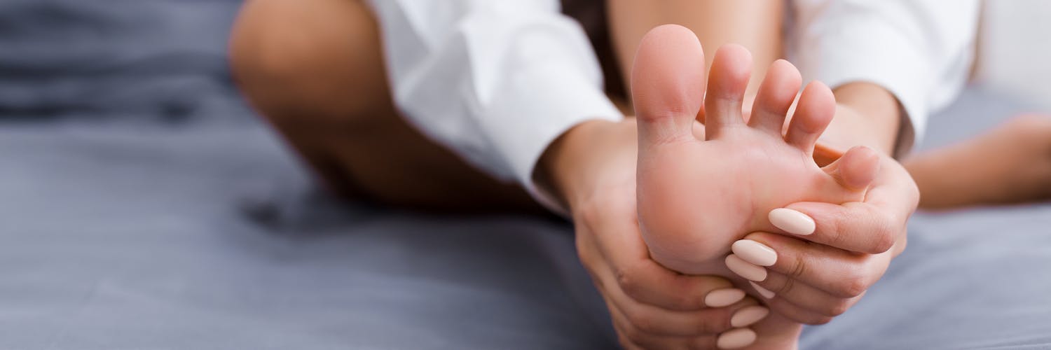 Frau greift sich an den schmerzen Fuß