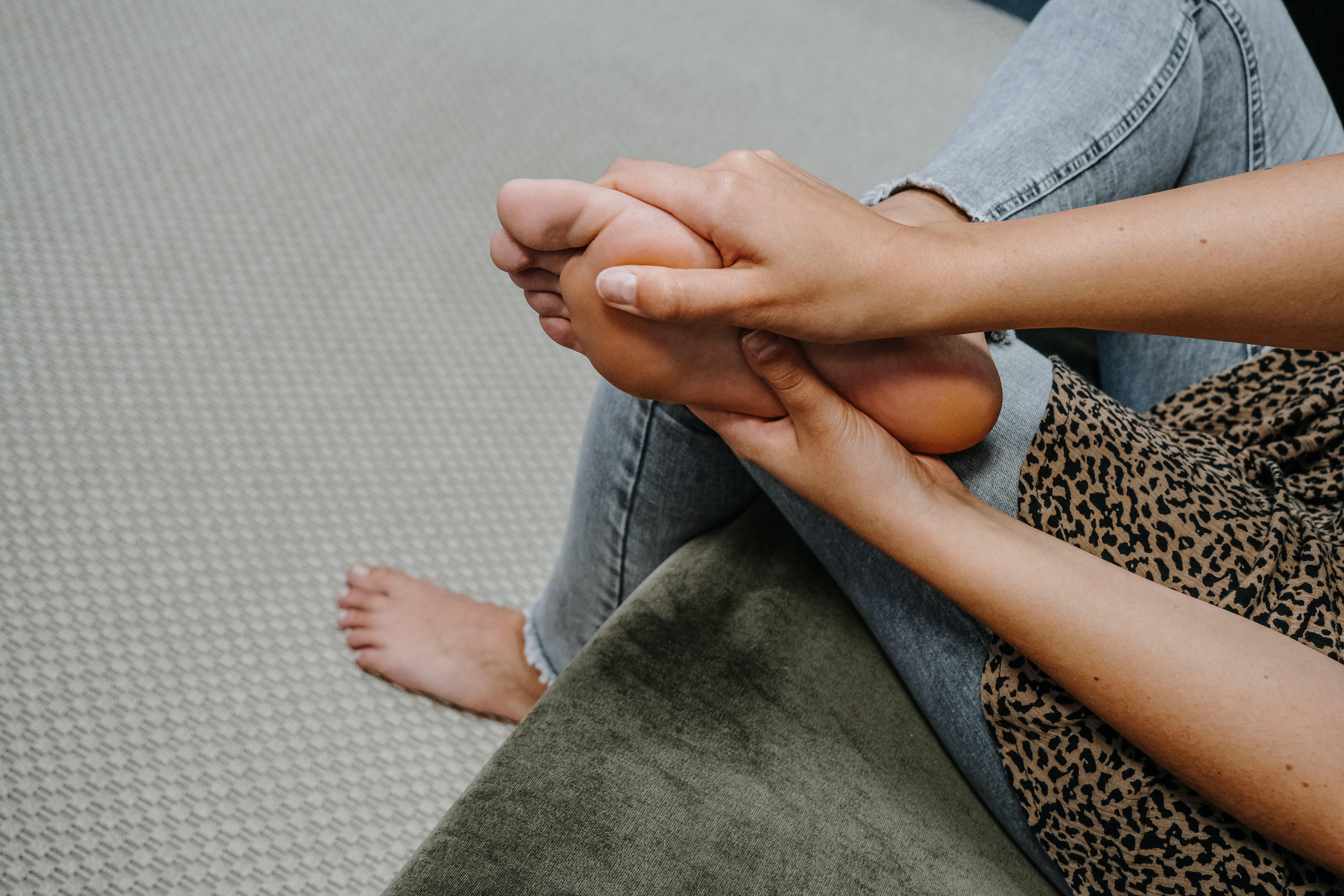 Frau greift sich im Sitzen an den Fuß