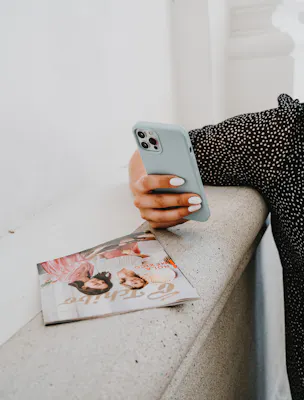 Frau lehnt sich mit Handy in der Hand an Mauer. 