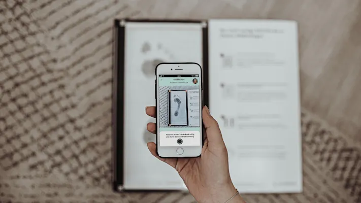 Mensch hält Handy in der Handy und fotografiert Abdruckset für Einlagen