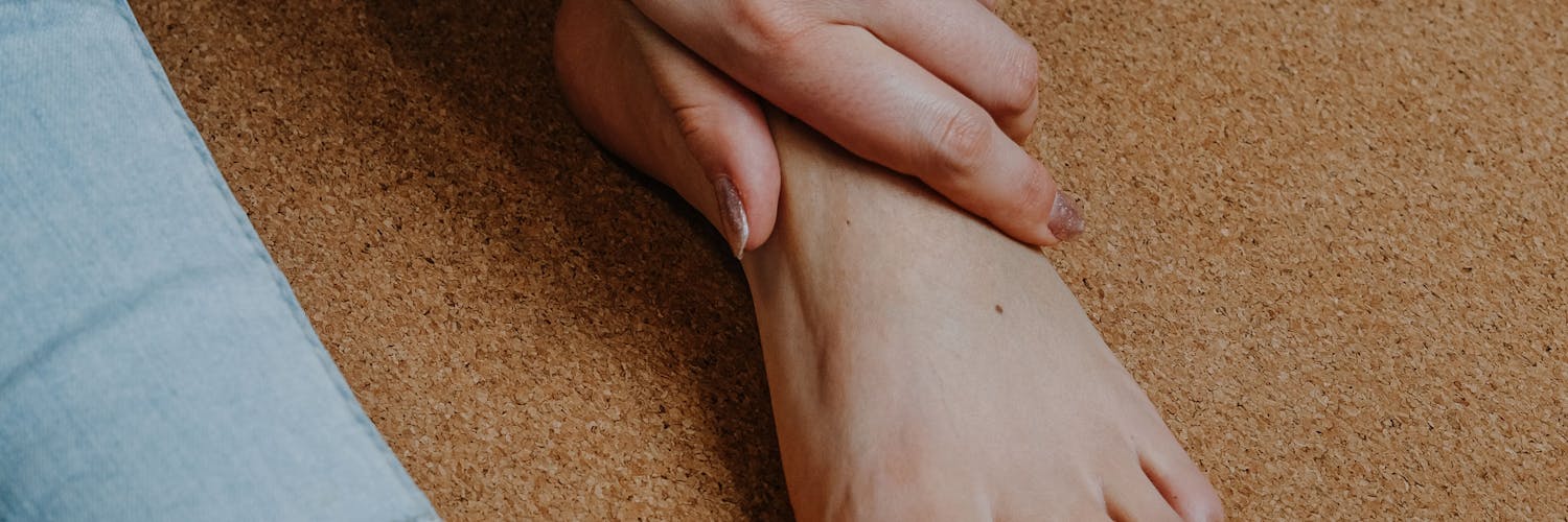 Frau greift sich an den schmerzenden Fuß