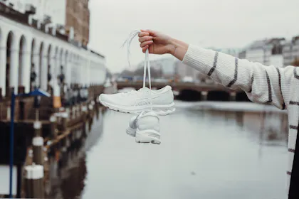 Frau hält Schuhe in der Hand.