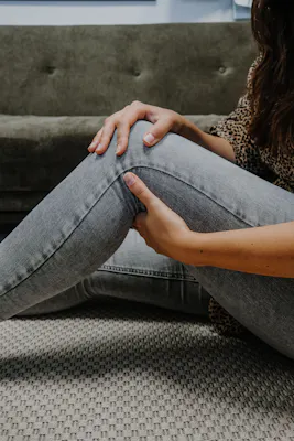 Frau greift sich an schmerzendes Knie