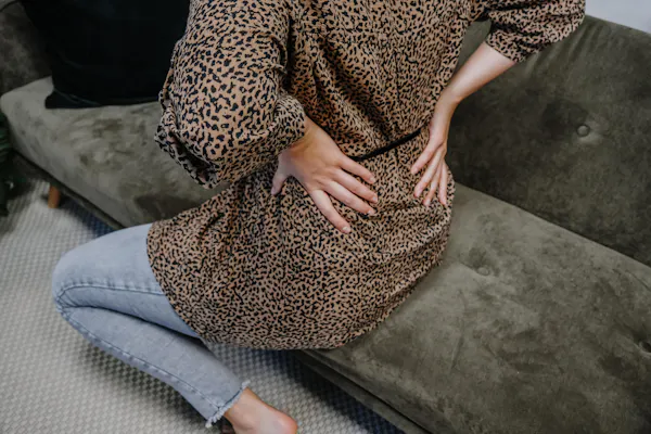 Frau greift sich vor Schmerz an die Hüfte