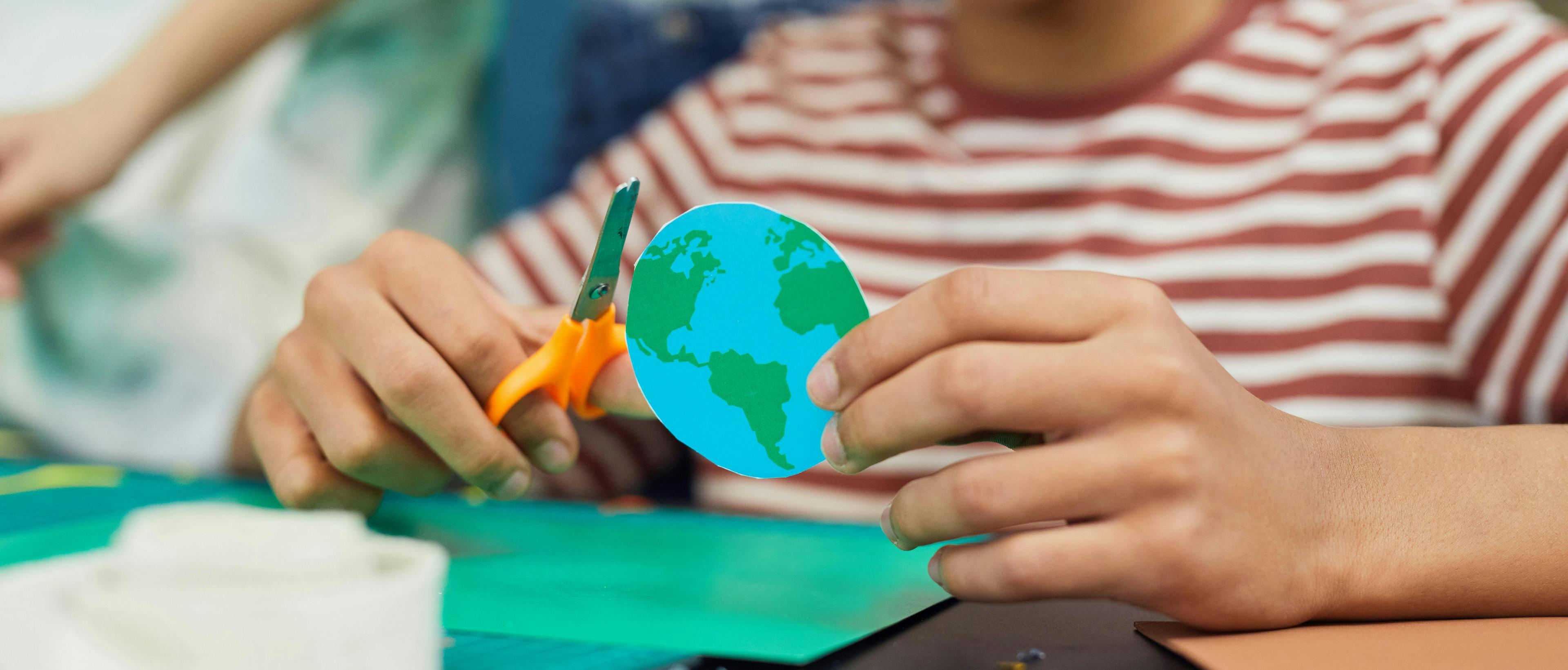 Young person holding a cut out of a planet Earth