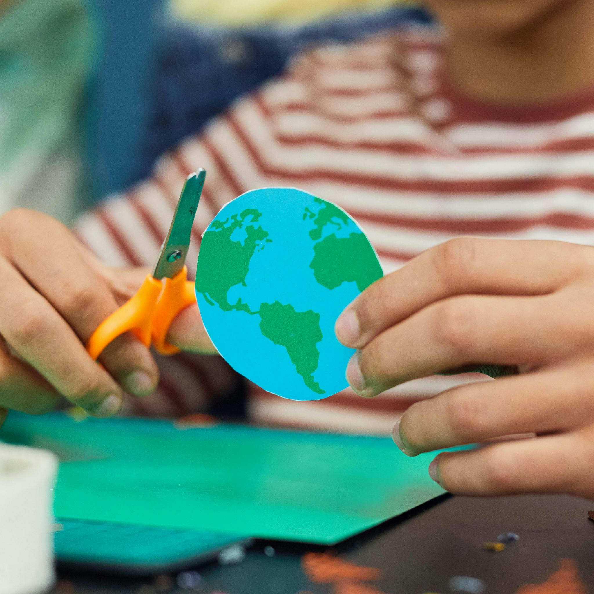 Young person holding a cut out of a planet Earth