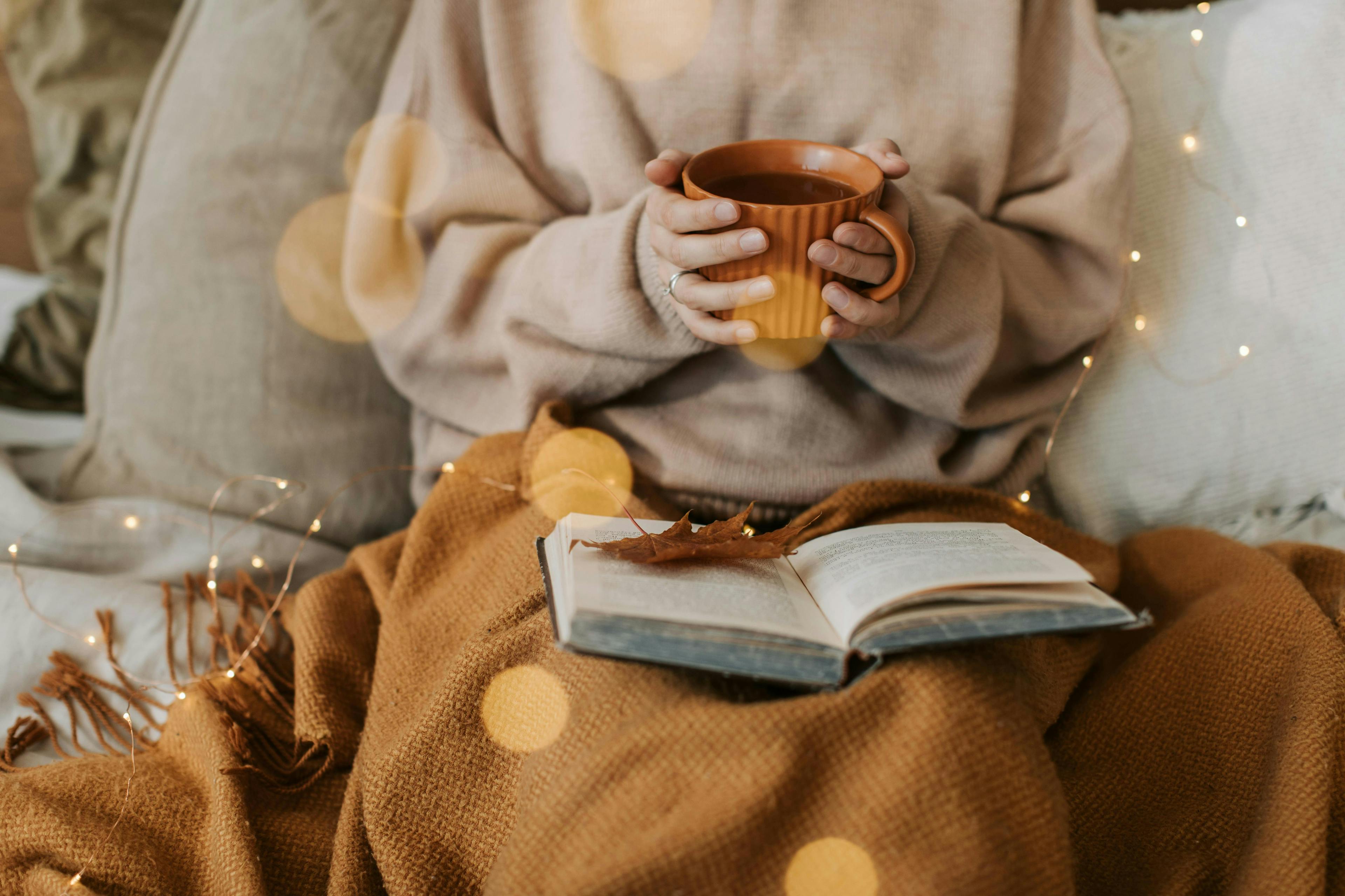 Girl in bed reading with the cup of coffee