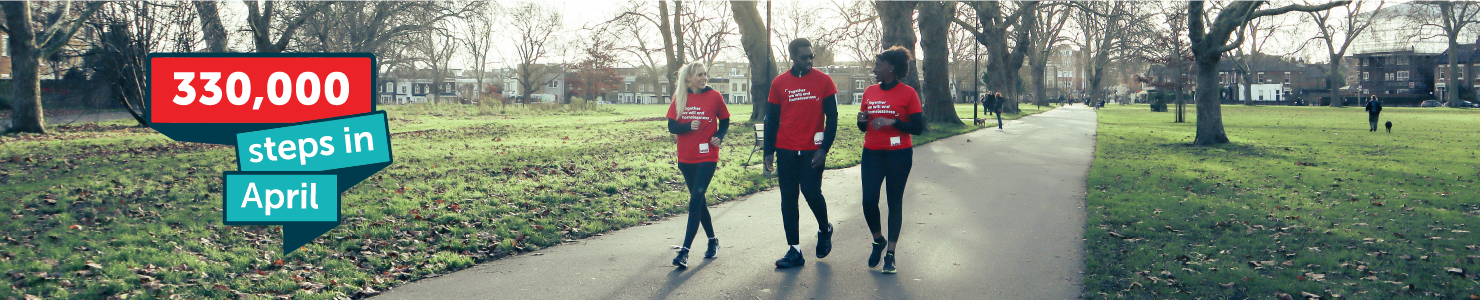 Two women and a man walk along a path in a park wearing red Crisis t-shirts. Overlaid logo reads ‘330,000 steps in April’.