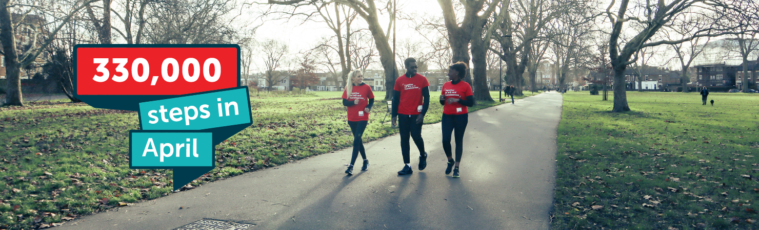 Two women and a man walk along a path in a park wearing red Crisis t-shirts. Overlaid logo reads ‘330,000 steps in April’.