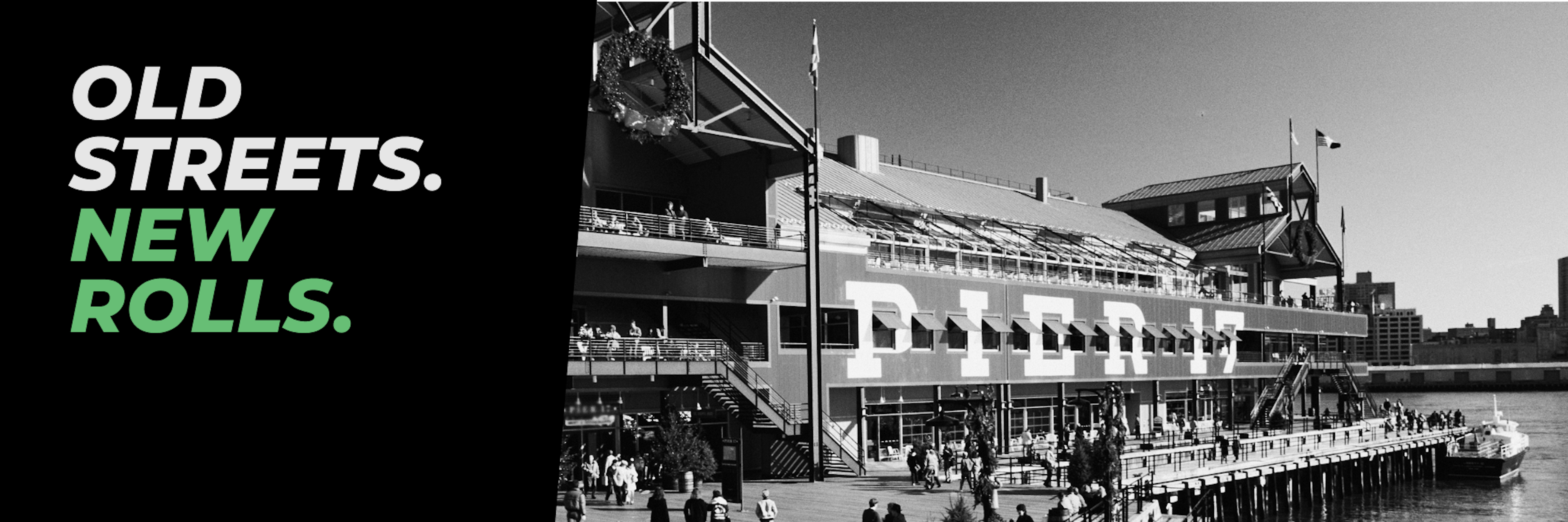 Black and white photo of Pier 17 at the South Street Seaport in New York City, with crowds walking along the boardwalk and a docked boat in the water. Bold text on the left reads: “OLD STREETS. NEW ROLLS.” with “NEW ROLLS.” highlighted in green.