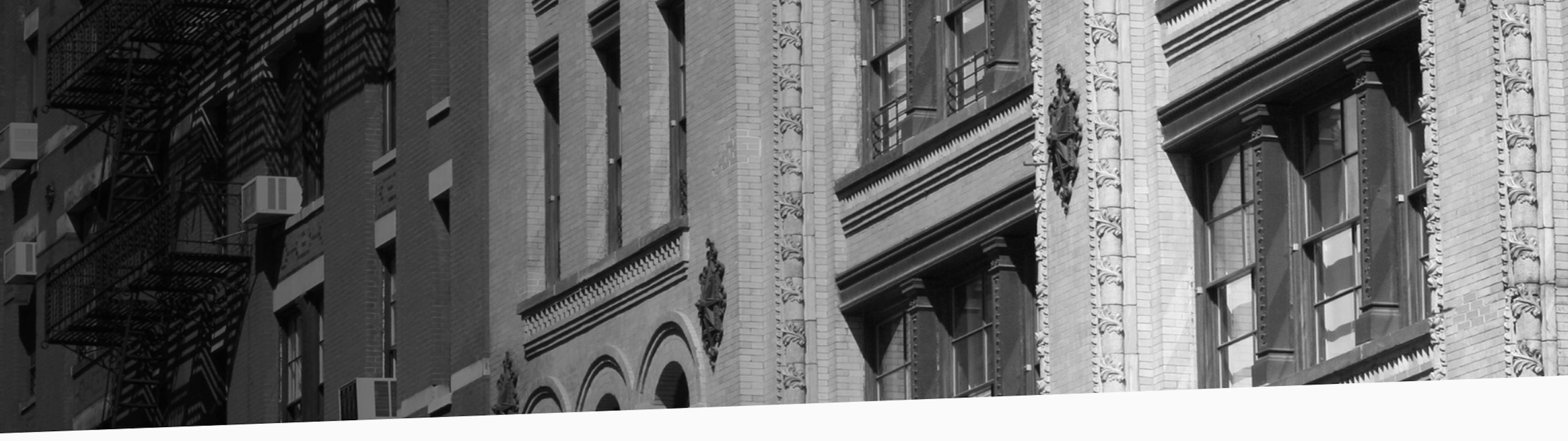 Black and white photo of historic brick and stone building facades in New York City, with decorative molding and tall windows.