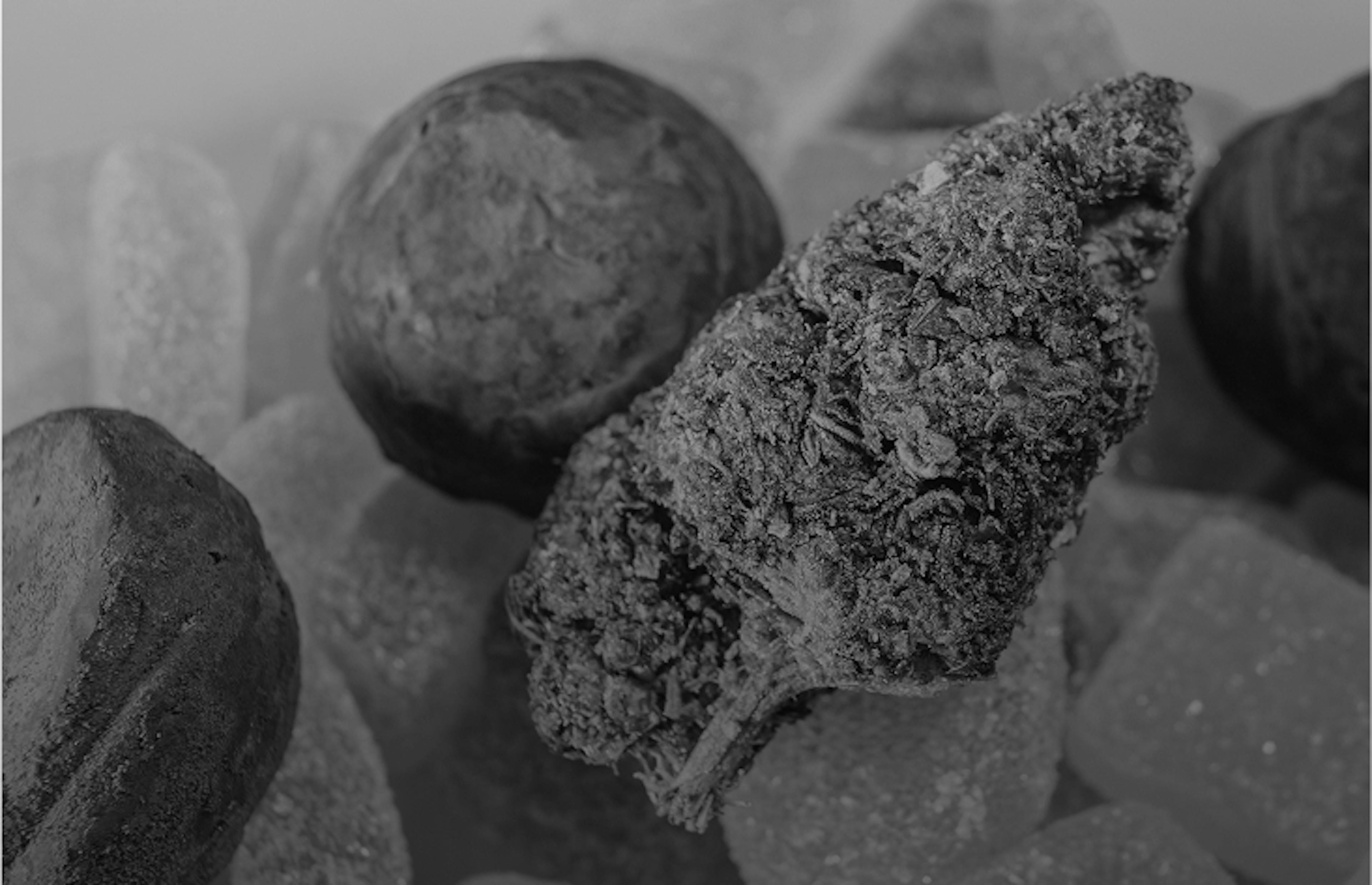 A cannabis bud displayed with infused edibles like gummies and chocolate truffles.