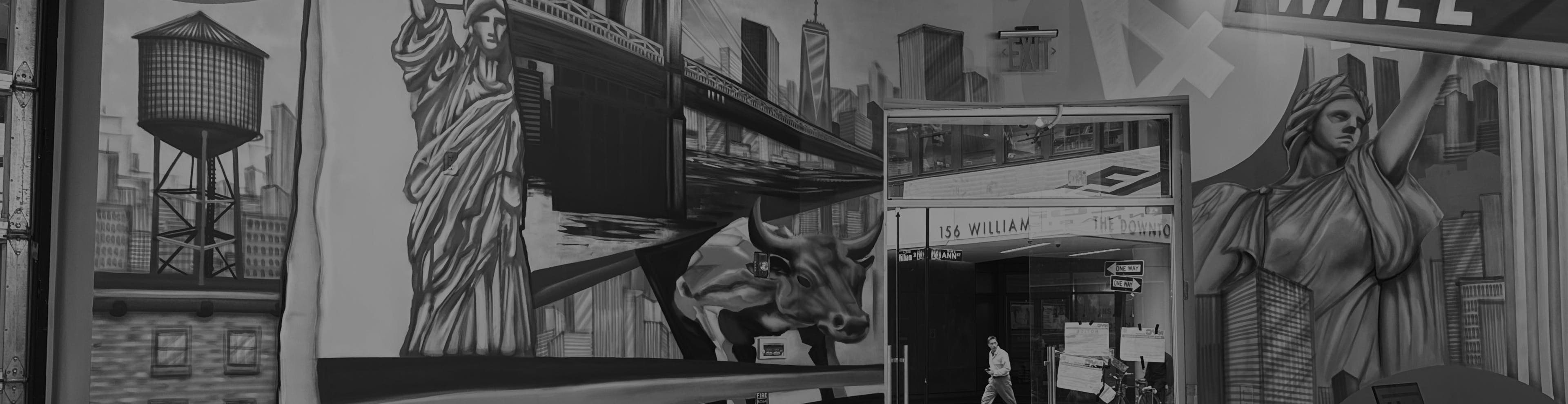 Black-and-white mural of New York City inside a dispensary, featuring large-scale illustrations of the Statue of Liberty, Wall Street sign, Brooklyn Bridge, NYC skyline, water tower, and the Charging Bull. The mural wraps around a corner wall and frames a glass exit door leading to 156 William Street.