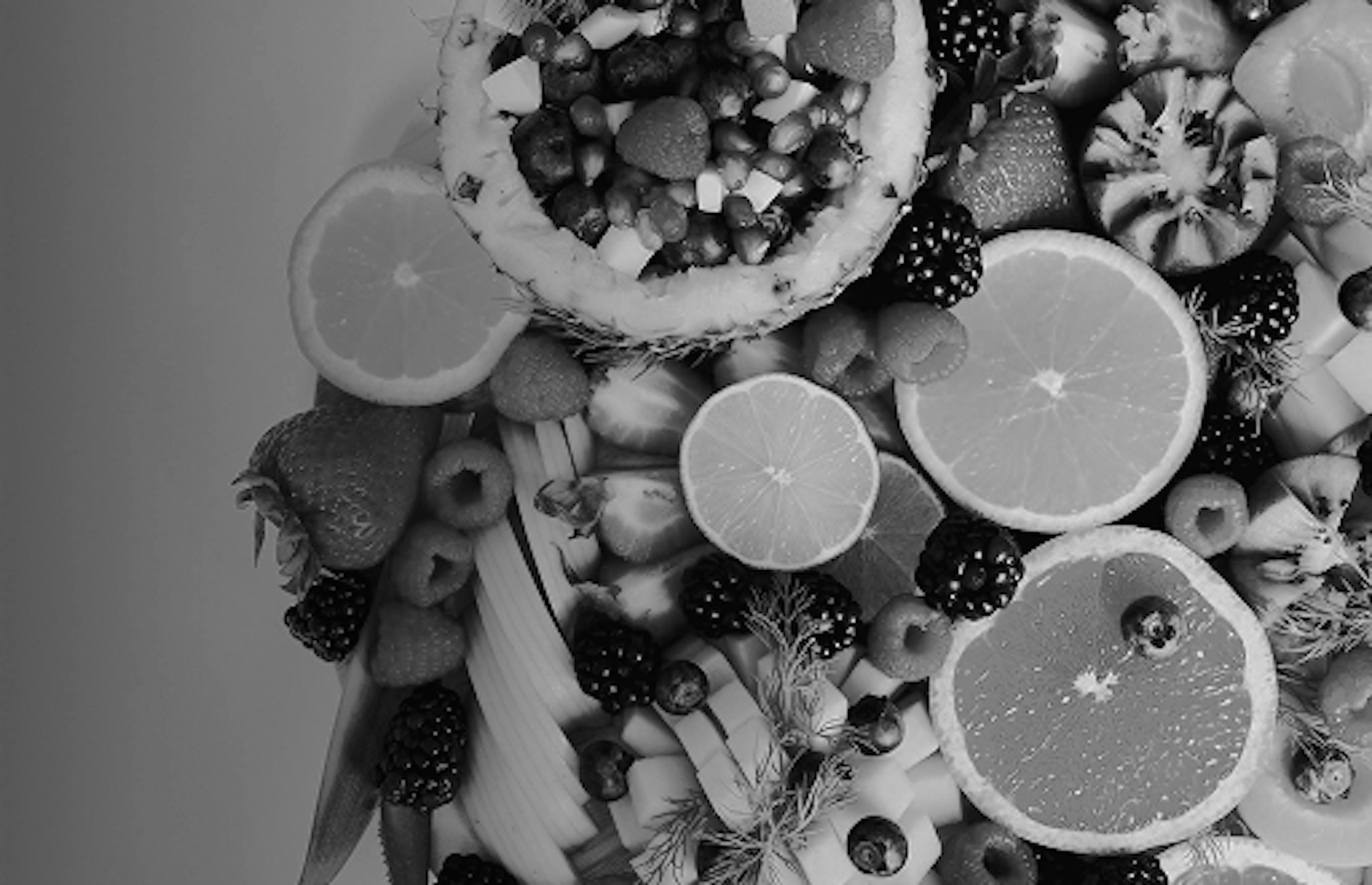 Assorted sliced fruits including oranges, blackberries, raspberries, and pineapple arranged in a colorful display.