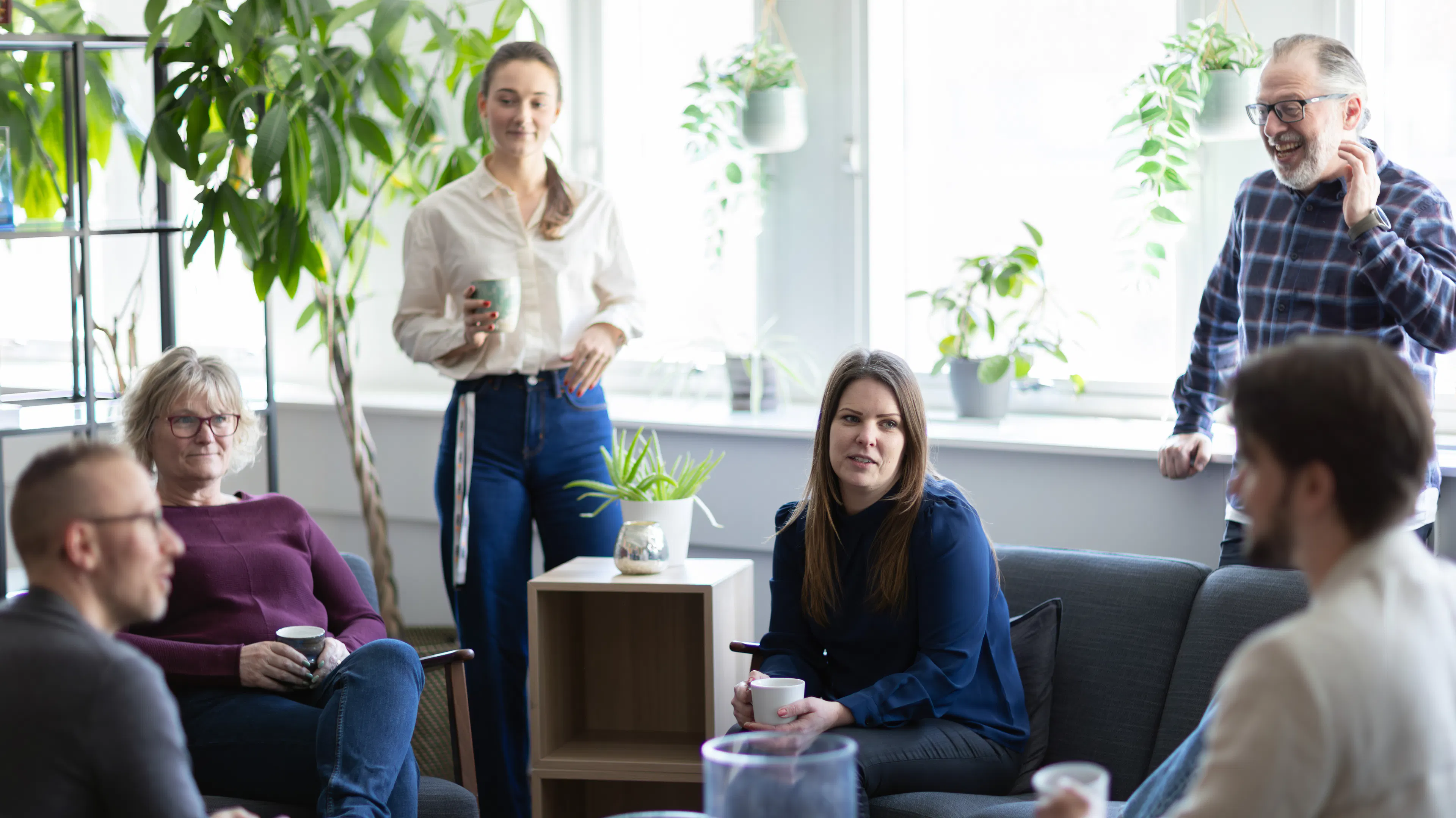 Grupp som sitter och fikar i ett kontorslandskap.