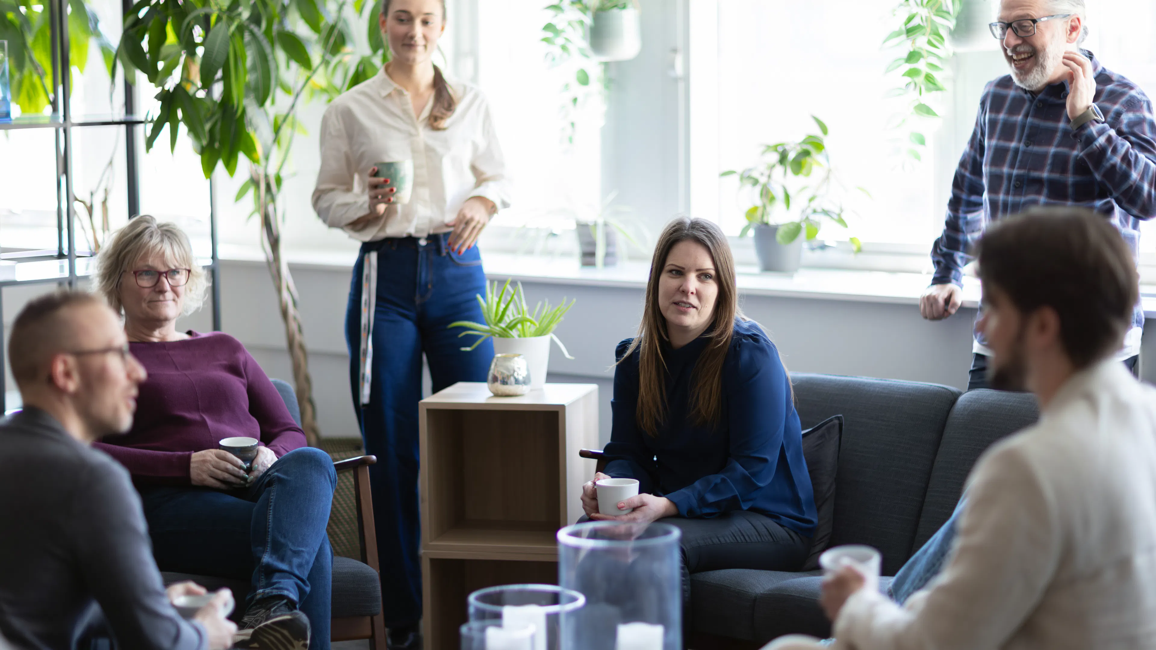 Grupp som sitter och fikar i ett kontorslandskap.