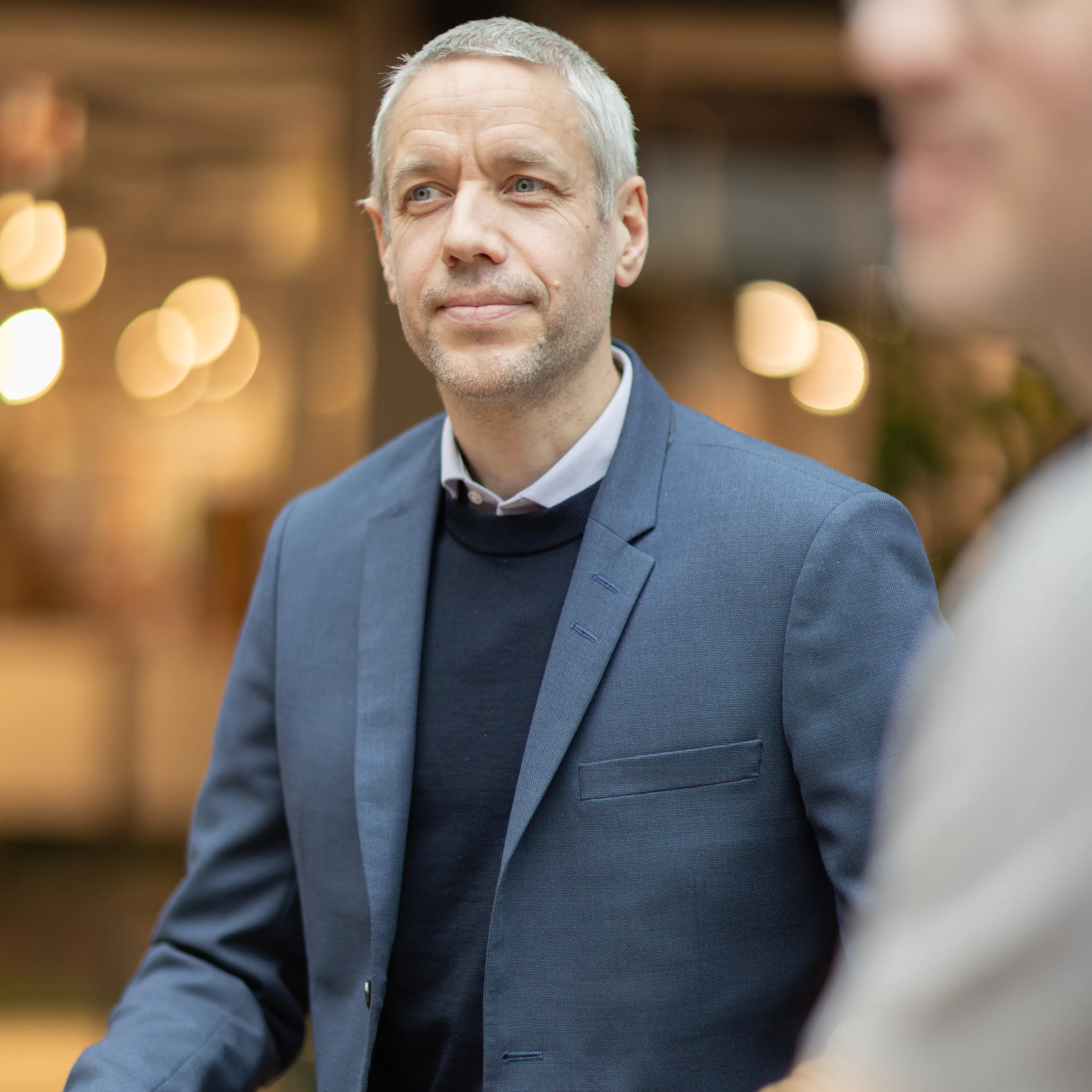 Man med kort grått hår klädd i blå kavaj